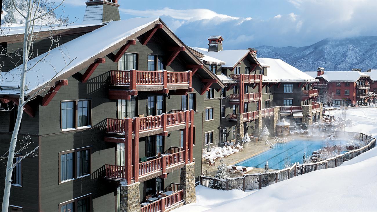 Exterior of The Ritz-Carlton Club Aspen Highlands resort timeshare showing snow-covered grounds and steam rising from pool